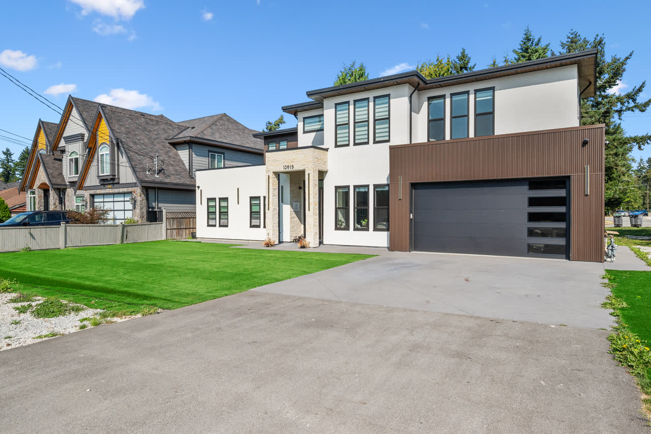 Contemporary two-storey home in white stucco and dark timber cladding, with a double garage and wide concrete driveway