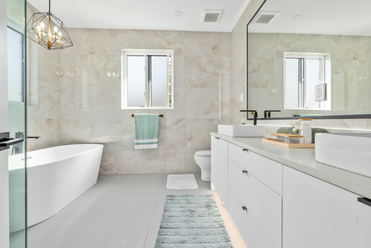 Marble-clad bathroom with a freestanding soaking tub, twin vessel sinks and a glass shower enclosure