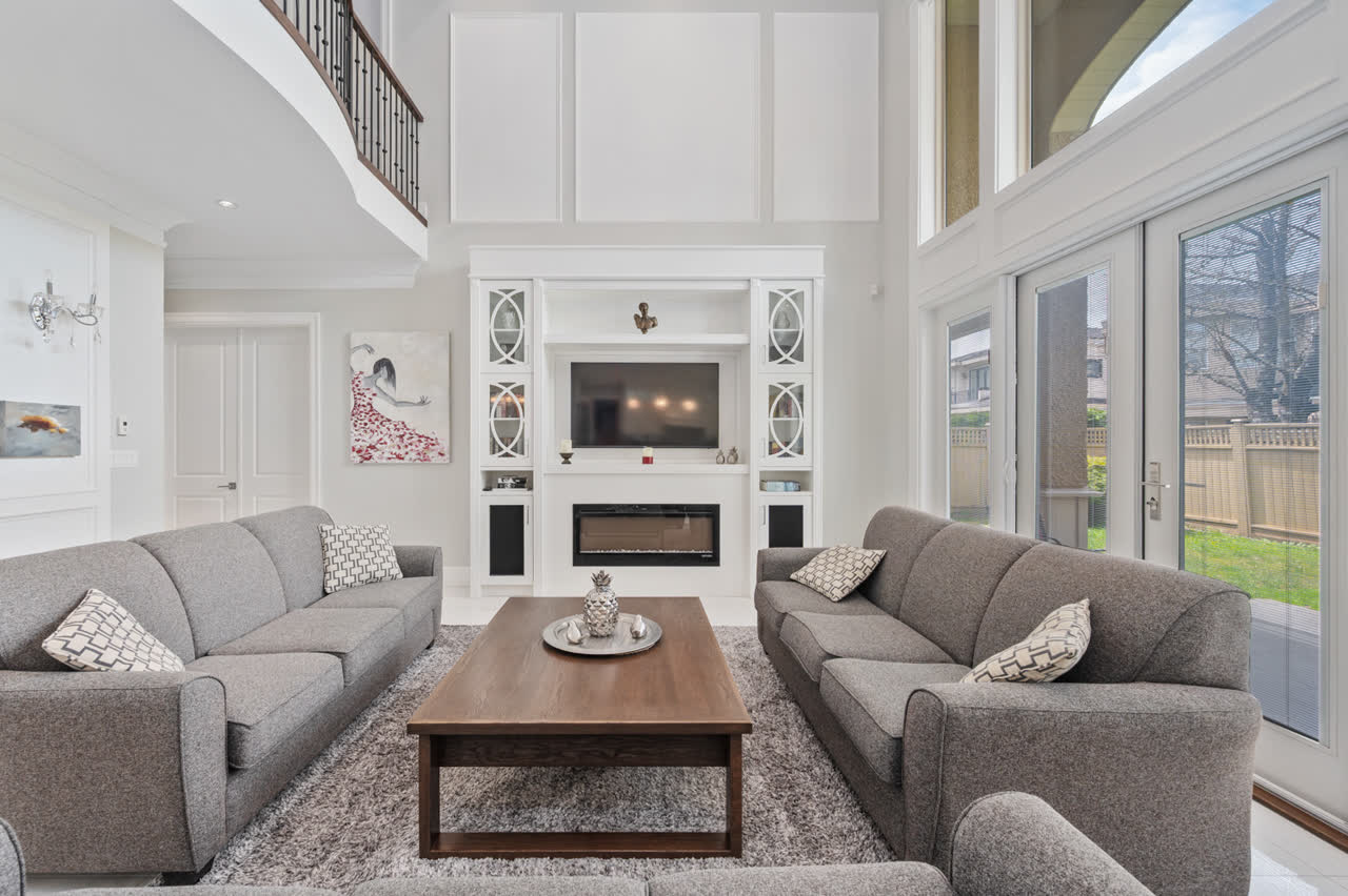 Double-height living room with twin grey sofas, a linear fireplace and a staircase landing overlooking the space